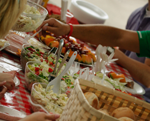 family around picnic table with food​ 