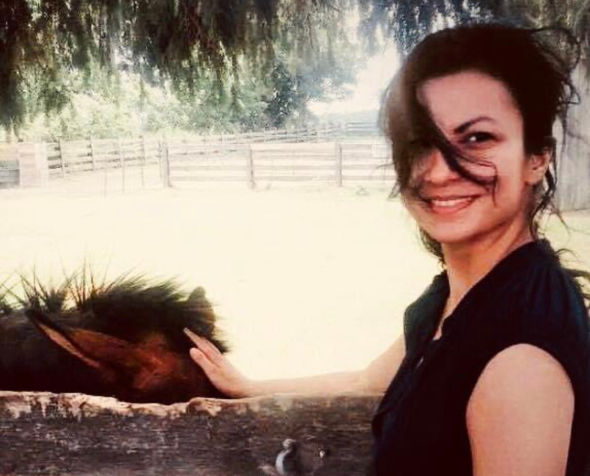 Mel Choubak standing outside petting a pony