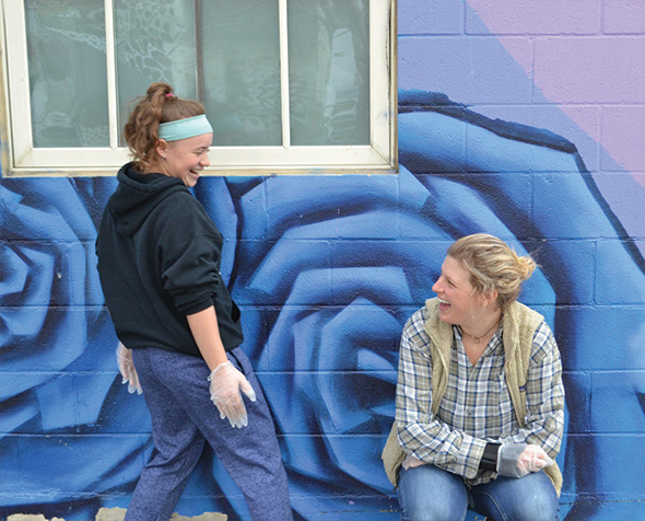 Mentor and Teen laughing in front of a mural