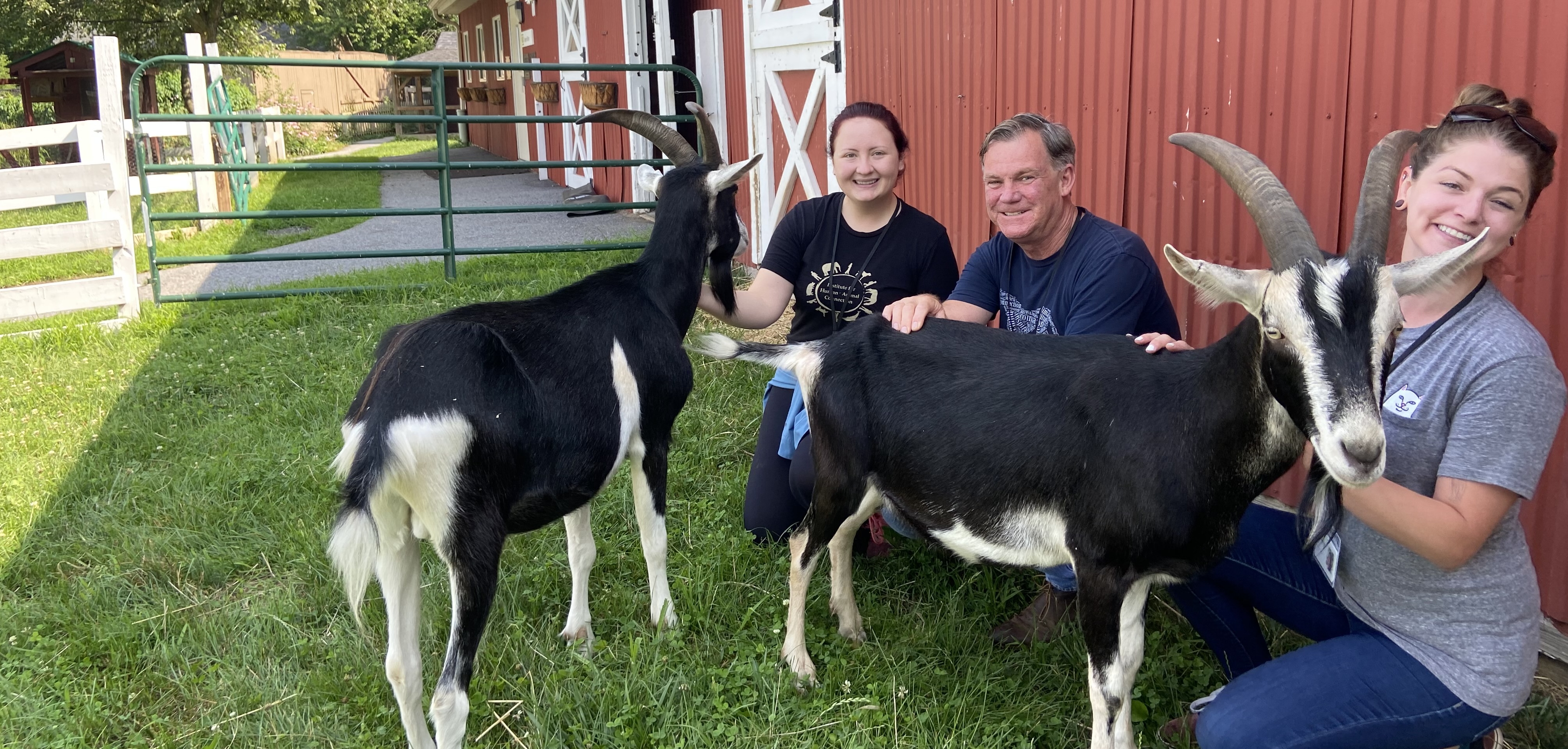 three people with two goats