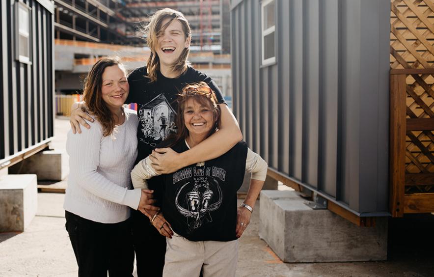 three people standing together in group hug