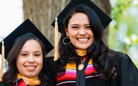 Two graduating students dressed in regalia