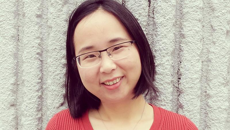 Woman with black medium length hair and glasses smiling. 