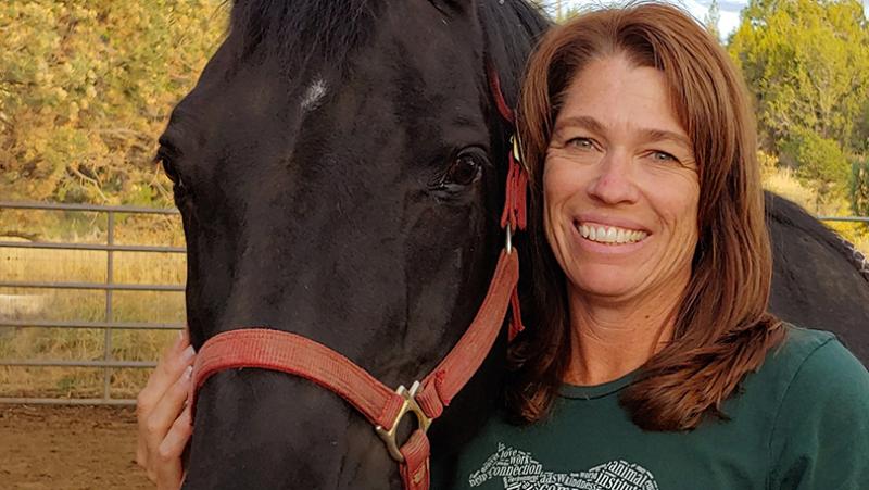 woman next to horse smiling. 
