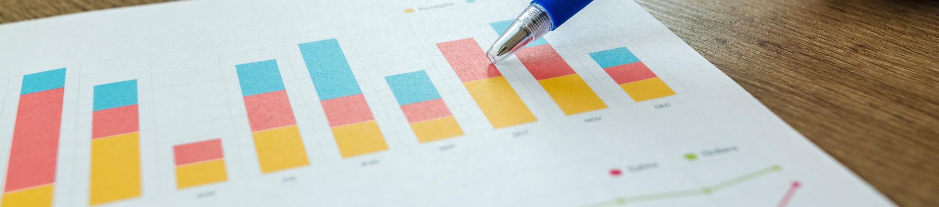hand holding pen pointing at graph on paper
